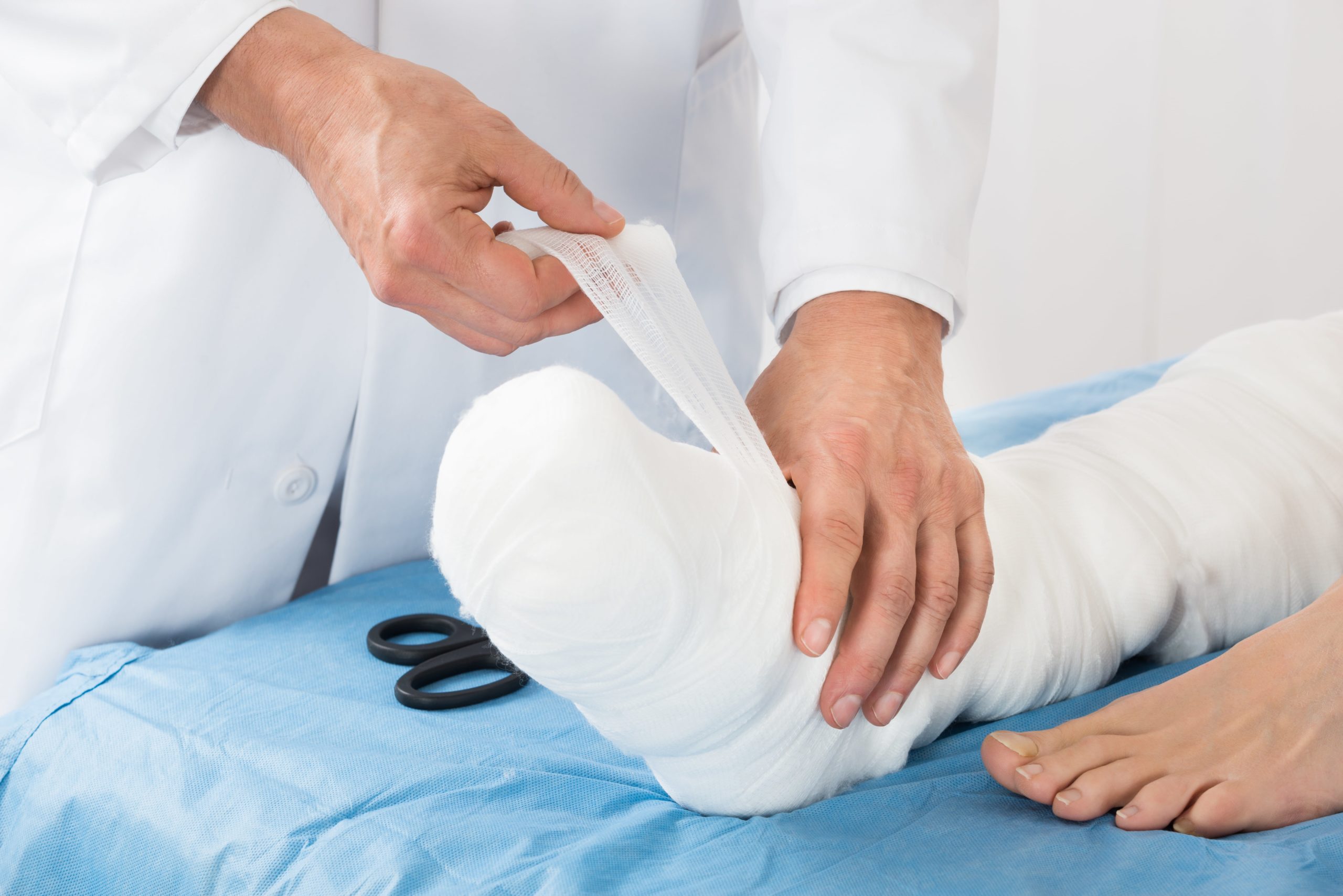 Doctor tying bandage on the leg of patient.