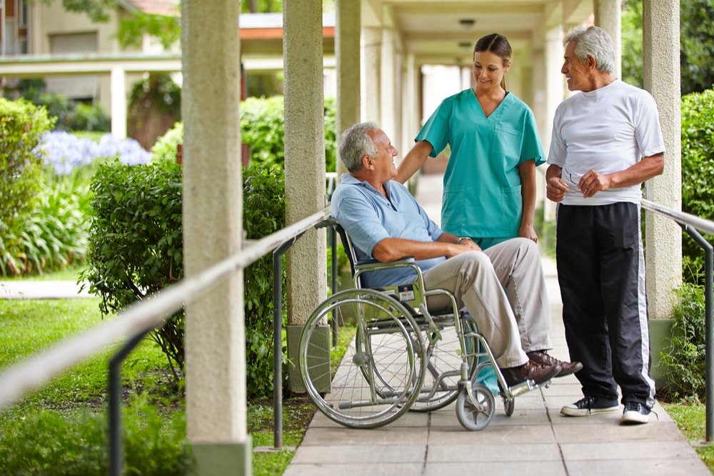 Elders and a nurse talking outside in the nursing home.