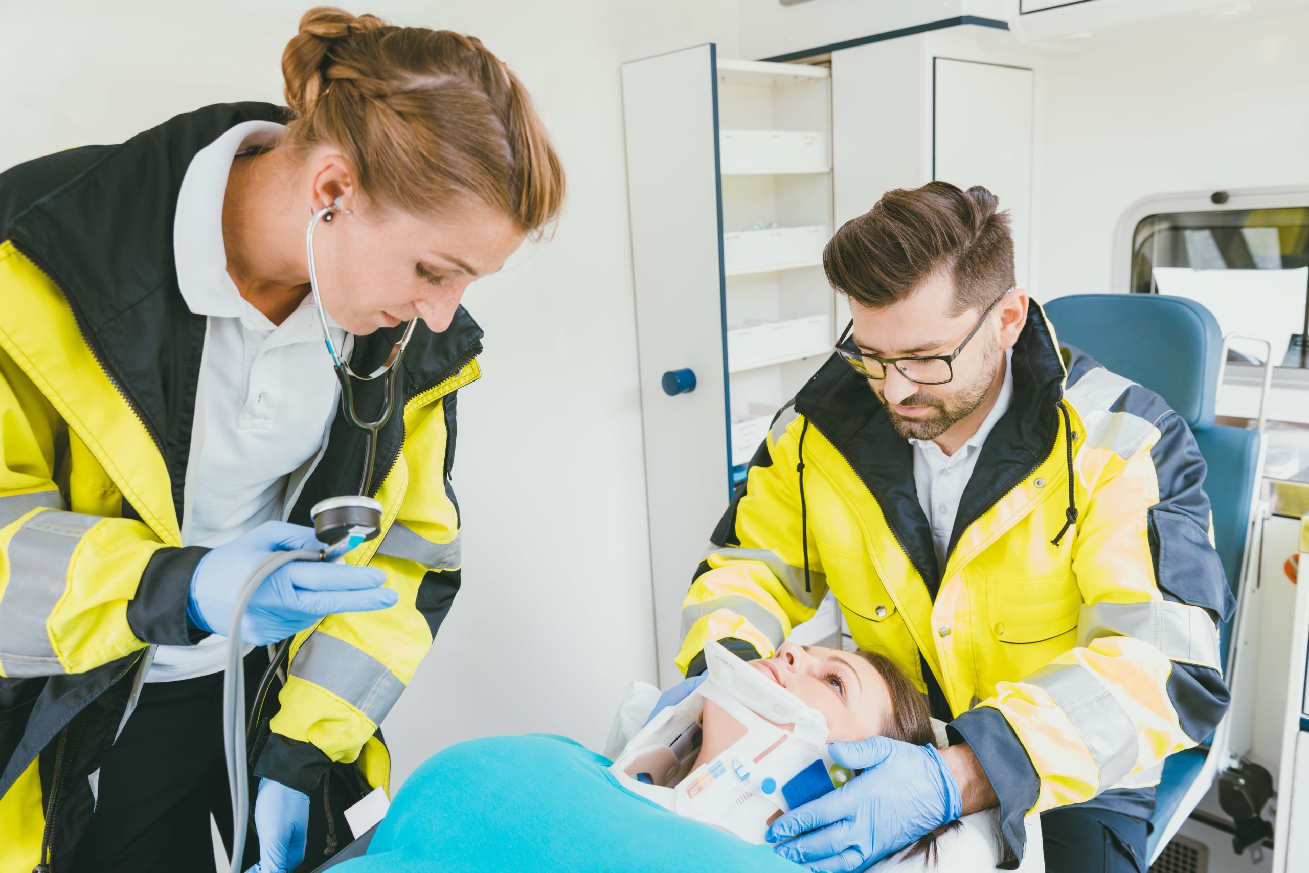 Medic taking care of injured woman with whiplash collar in ambulance.