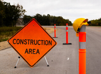 a highway construction zone with barricades and warning signs