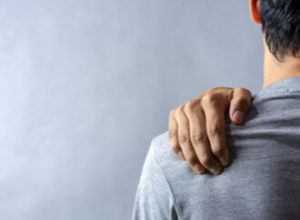 a man holding his shoulder due to pain from shoulder pump