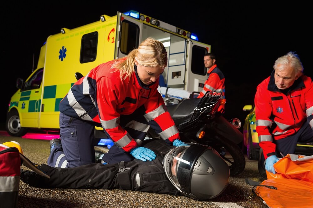 Paramedics rescuing injured motorcycle rider.