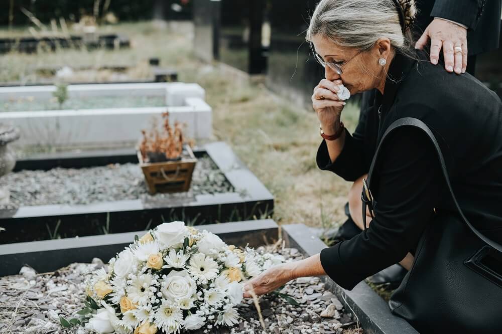 Grieving woman who lost her husband offering flowers