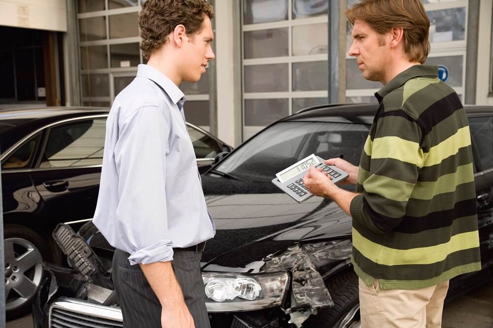 Insurance adjuster checking on damages from car accident.