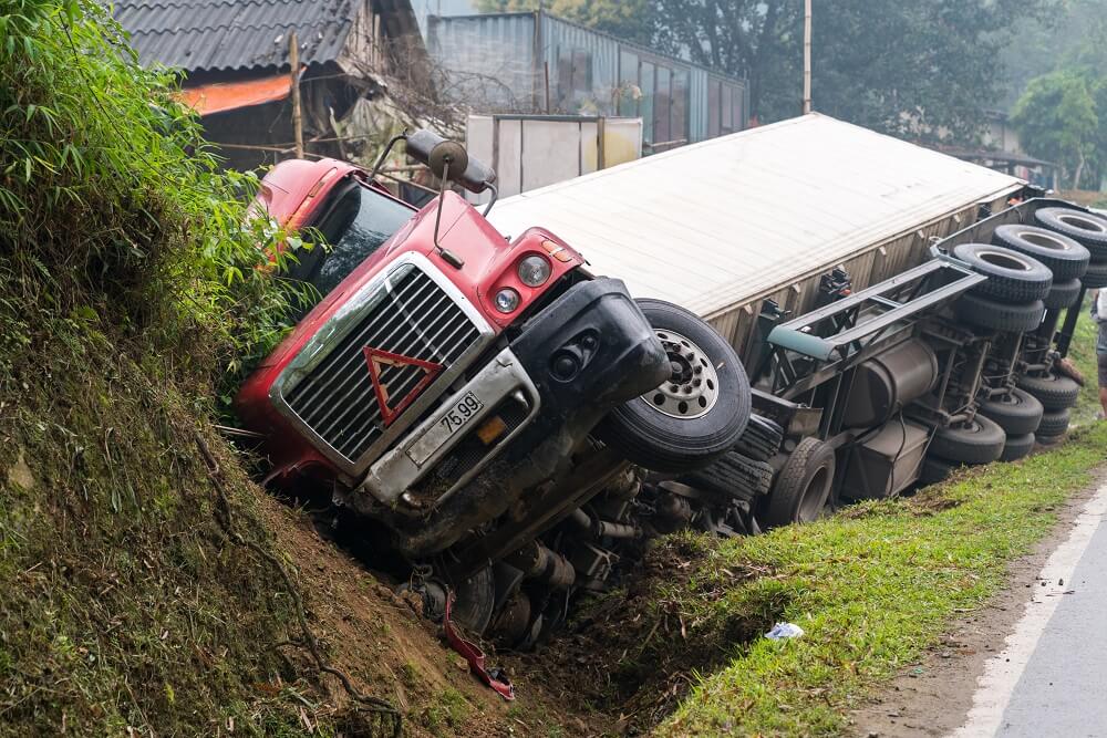 Red truck overturned and lying on side in a ditch