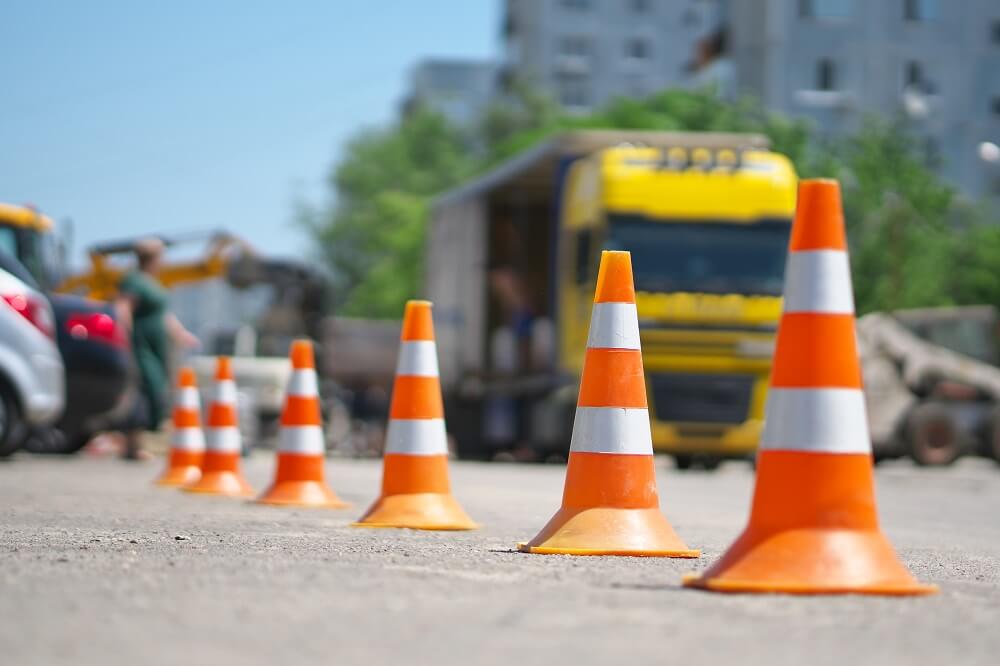 Row of traffic cones in the road and truck passing.