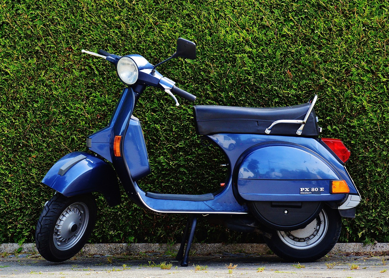 a moped parked by a hedge