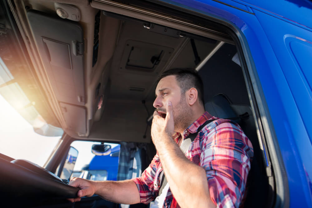 Truck driver yawning while driving.