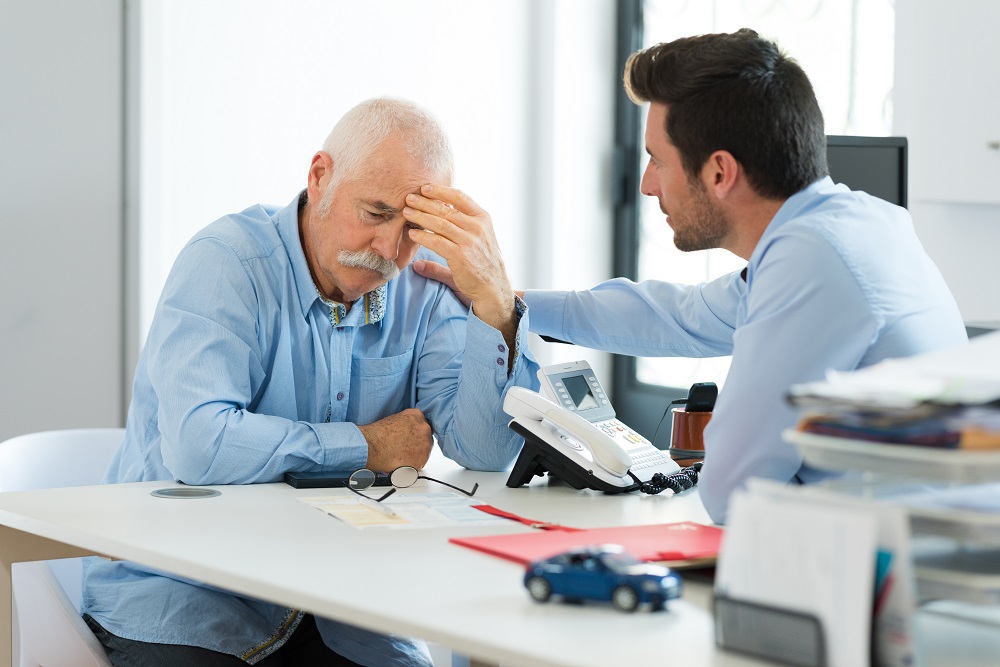 Worried senior driver talking to his insurance agent.