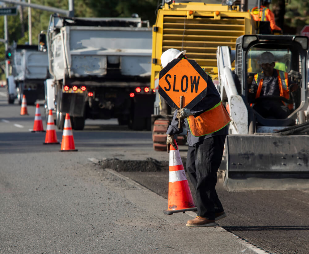 Road worker putting slow sign in the other lane to prevent accident.