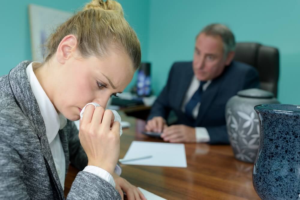 Lady crying at the funeral office on the death of her late husband.