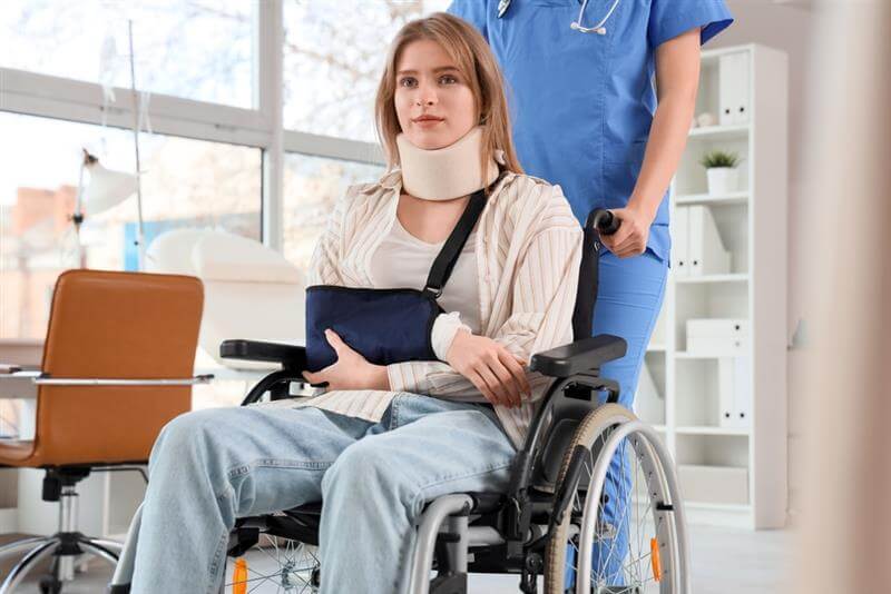 Injured young woman after accident in wheelchair with doctor at hospital.